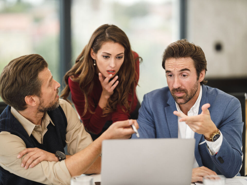 Colleagues looking at a report on a laptop